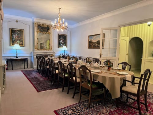 Elegante comedor formal en el Domaine de Bize con mesa servida, araña de cristal, chimenea y obras de arte de época en Mirepoix, Ariège.
