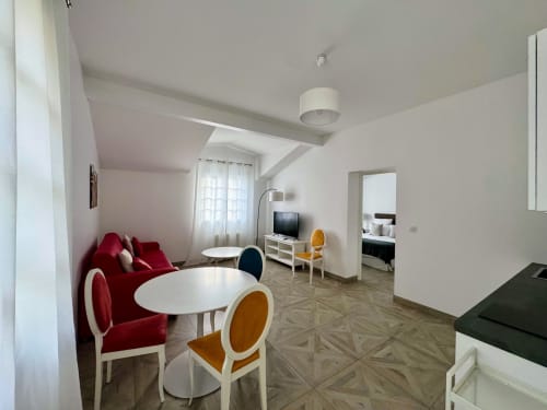 Sala de estar moderna con sofá rojo, mesas redondas blancas y sillas amarillas en Domaine de Bize Mirepoix