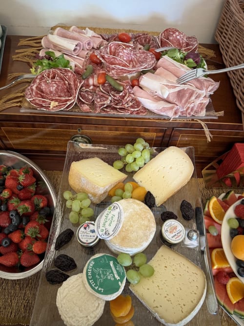 Tabla gourmet de embutidos y quesos en un palacio francés con carnes curadas, quesos artesanales, uvas y frutas frescas