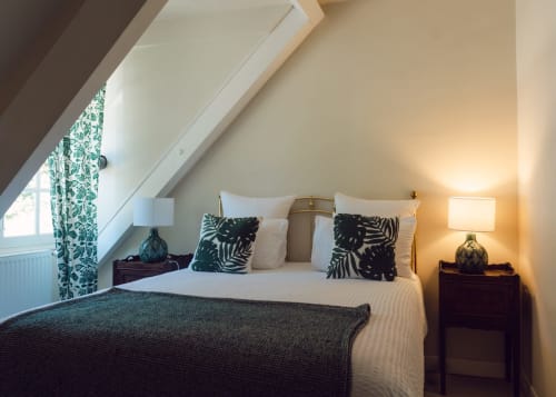 Acogedora habitación bajo las vigas en Domaine de Bize con vistas al jardín, cojines decorativos e iluminación cálida en Mirepoix