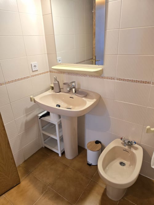 Salle de bain moderne dans un appartement en bord de mer à Roses avec lavabo colonne, bidet, miroir rétroéclairé et carrelage