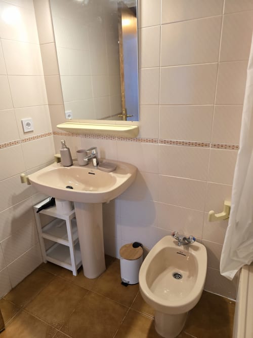 Salle de bain moderne avec lavabo sur colonne, bidet et miroir lumineux dans l'appartement Rosas près de la plage