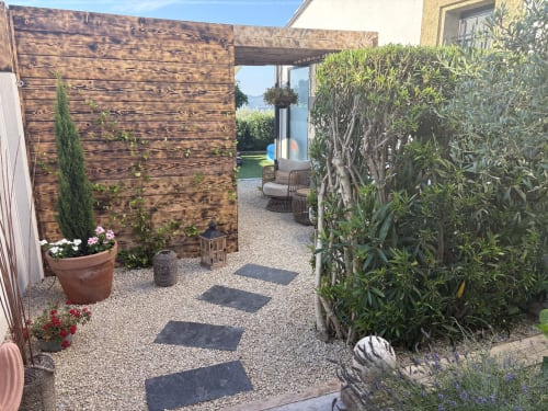 Allée moderne de la terrasse de l'hôtel Muriel MARCONE à Puyvert avec gravier, pergola en bois et verdure luxuriante