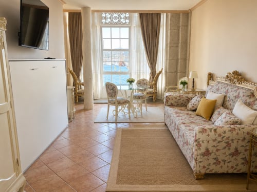 Elegante apartamento frente al mar en Baiona con vista al océano, sofá floral, comedor y amenidades modernas