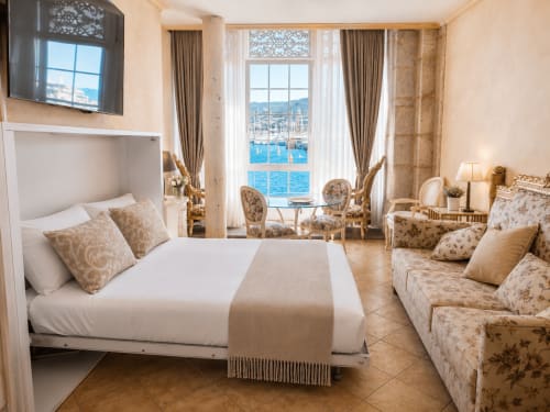 Apartamento de lujo frente al mar en Baiona con vistas al puerto, cama, sofá y ventanal