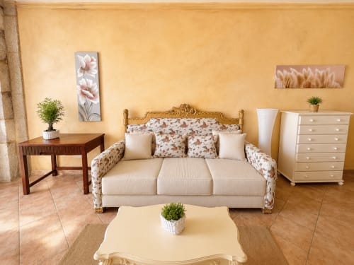 Elegante sala de estar en apartamento frente al mar en Baiona con sofá floral, muebles crema y arte decorativo en pared