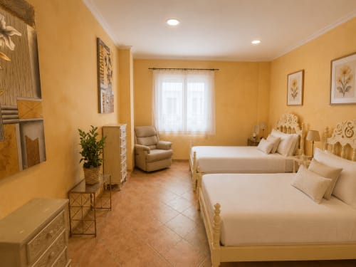 Espacioso dormitorio en apartamento frente al mar en Baiona con camas gemelas, paredes amarillas, vistas al mar y comodidades modernas incluyendo TV y