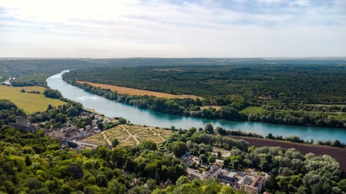 Aerial view of La Roche Guyon with turquoise river, lush forests, and historic château in Giverny region