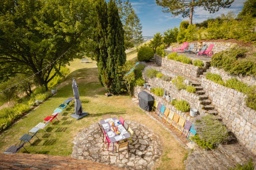 Terrasse de jardin au Paradis de Lucile avec chaises roses, table dressée et murs en pierre à La Roche Guyon, France