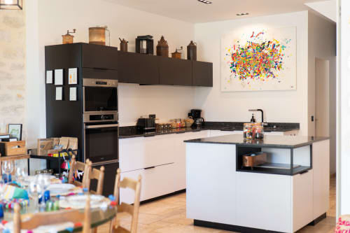 Cuisine moderne aux meubles noir et blanc, œuvres colorées et îlot central, Le Paradis de Lucile BnB à La Roche
