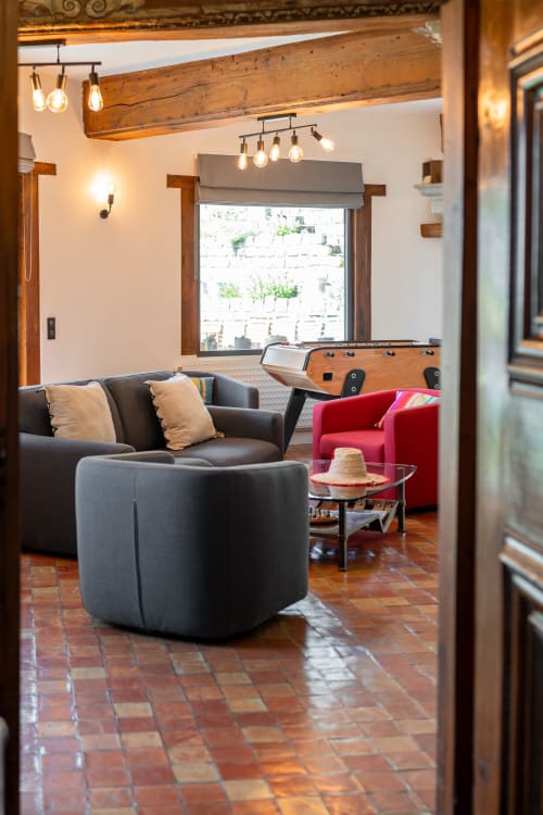 Salle de jeux rustique avec poutres apparentes, baby-foot et fauteuil rouge au Paradis de Lucile, La Roche Guyon