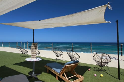 Lounge frente al mar Vidasoul con toldo vela crema, sillas negras, tumbona de madera y vista al océano en La Vinorama, México
