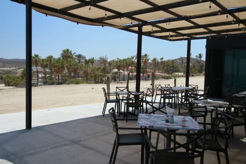 Patio Vidasoul con mesas de comedor, pérgola negra, paisaje desértico y palmeras en La Vinorama