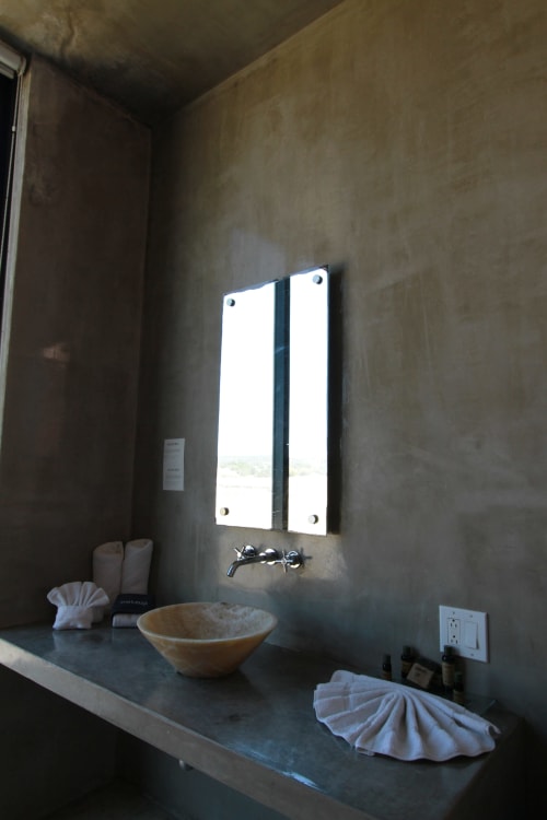 Moderno lavabo del baño en Vidasoul BnB en La Vinorama con espejo iluminado, lavamanos de piedra y vista al mar