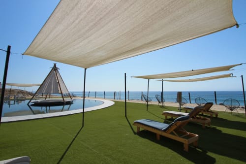 Lounge frente al mar Vidasoul con velas de sombra, vista al océano, tumbonas de madera y fogata cónica en La Vinorama, México