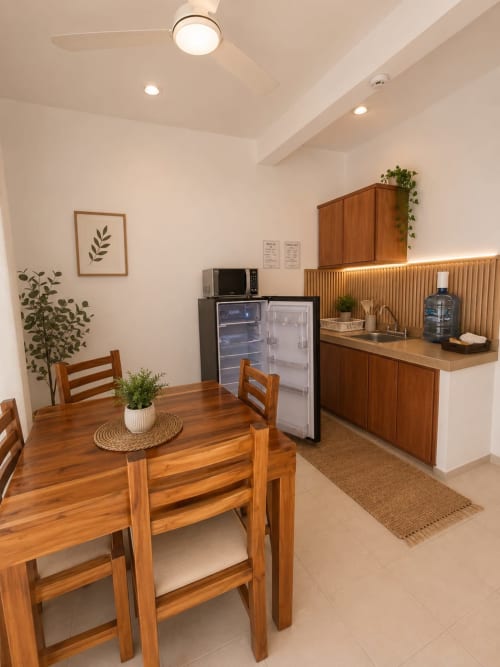 Suite moderna en Hotel Isla Mujeres Centro con mesa de comedor de madera, kitchenette con refrigerador y decoración botánica.