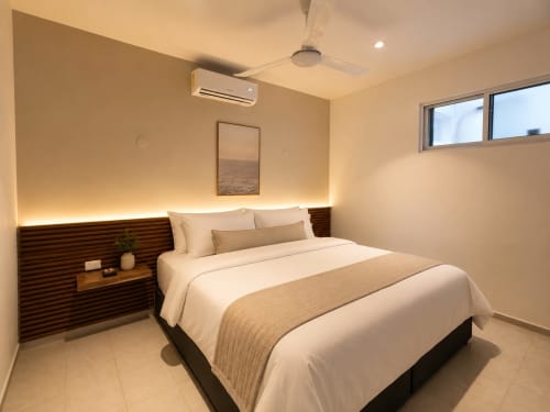 Moderna suite de hotel en Hotel Isla Mujeres Centro con cama queen, iluminación cálida y aire acondicionado