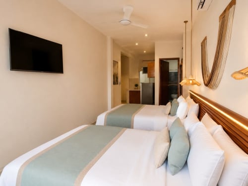 Habitación moderna del Hotel Isla Mujeres Centro con camas gemelas, TV pantalla plana y vistas a la ciudad