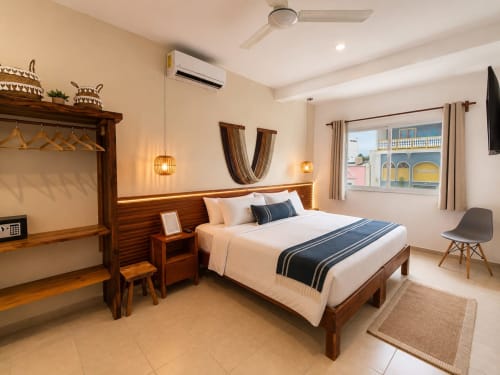 Moderna habitación de hotel en Hotel Isla Mujeres Centro con cama de madera, vista a la ciudad, aire acondicionado, lámparas colgantes y mobiliario contemporáneo