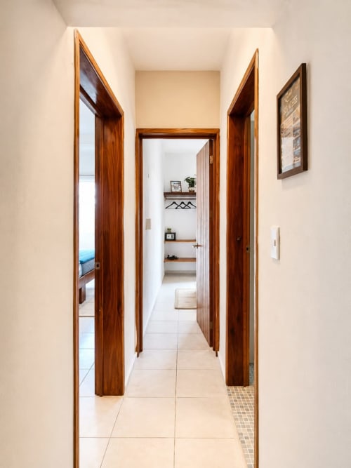Pasillo de suite en Hotel Isla Mujeres Centro con puertas de madera hacia dormitorio y baño, con acceso a vista de la ciudad
