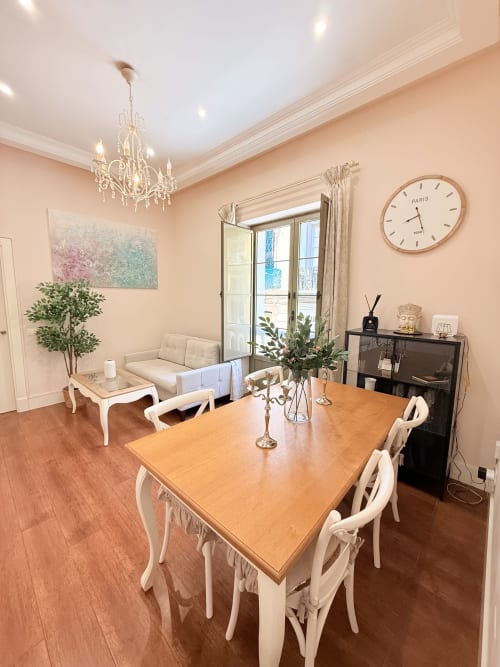 Elegante comedor de Madre de Dios Premium en el centro histórico de Málaga, con mesa de madera, sillas color crema y vistas a la ciudad