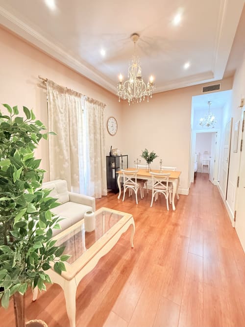Elegante comedor y sala de estar en Madre de Dios Premium en Málaga con suelos de madera, lámpara de araña y mobiliario moderno