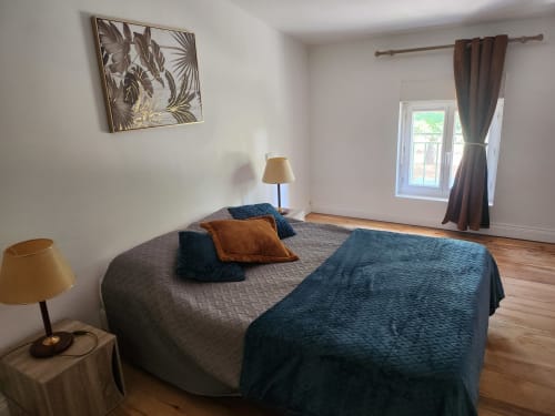 Spacious bedroom at Domaine De Poulharies B&B in Carcassonne with queen bed, blue accents, and glass door to terrace