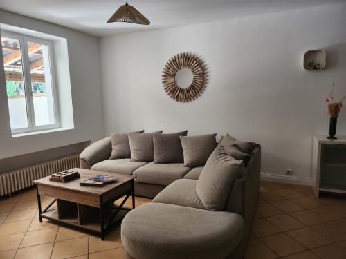 Modern living room at Domaine De Poulharies cottage with beige sectional sofa, wooden table, and decorative mirror in