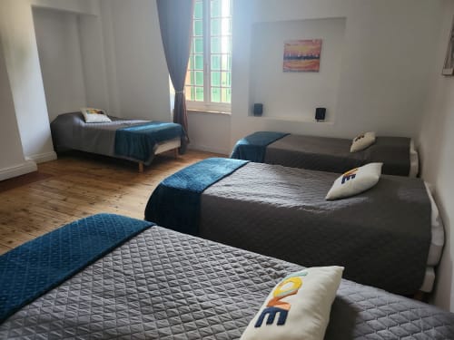 Spacious bedroom at Domaine De Poulharies cottage in Carcassonne with multiple beds, wooden floors, blue accents, and garden