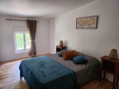 Bright bedroom at Domaine De Poulharies cottage in Carcassonne with blue bedding, wooden furniture, and garden view through