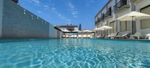 Piscina cristalina del Hotel Paraiso Playa en Isla Cristina con tumbonas, sombrillas y arquitectura mediterránea