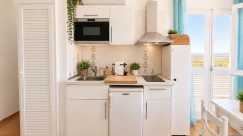 Cocina moderna y compacta en apartamento Holidays Sol & Brisa, Empuriabrava, con gabinetes blancos y electrodomésticos de acero inoxidable