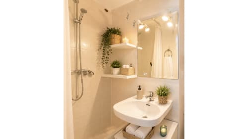 Baño moderno en Holidays Costa Brava con ducha, lavamanos blanco, espejo y plantas en maceta en Empuriabrava