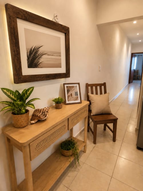Elegante pasillo de entrada en suite del Hotel Isla Mujeres Centro con consola de madera, plantas en maceta, cuadros enmarcados