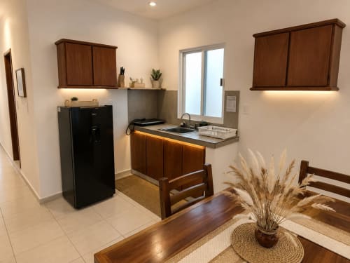 Cocina moderna con gabinetes de madera, refrigerador negro y encimeras de acero inoxidable en suite del Hotel Isla Mujeres Centro.