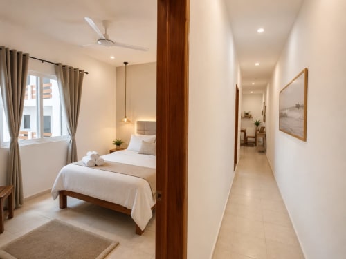 Suite moderna del Hotel Isla Mujeres Centro con cama individual, divisor de madera, pasillo hacia la zona de estar y vistas de la ciudad