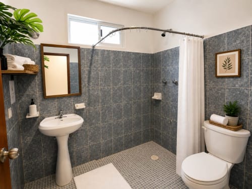 Baño moderno en Suite 6 del Hotel Isla Mujeres Centro con paredes de azulejos grises, lavamanos de pedestal, inodoro y ducha empotrada