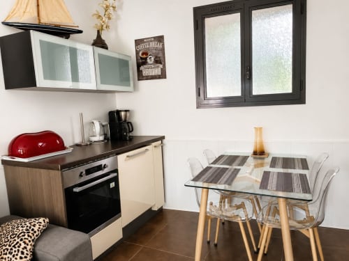 Modern keukentje met eethoek in het gasthuis Maison D'hôtes Coeur D'hérault, met zwart fornuis, rode waterkoker en