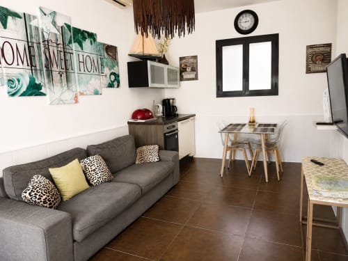 Modern open woongedeelte van een cottage in Péret met grijze bank, kitchenette, eettafel en huisdecoratie