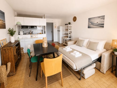 Studio moderne à La Loge Du Bassin, Cap Ferret avec cuisine, table à manger, canapé-lit et œuvre d'art vue mer.