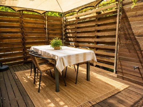 Privé buitenpatio van het gastenverblijf Maison D'hôtes Coeur D'hérault in Péret met eettafel en houten schermen