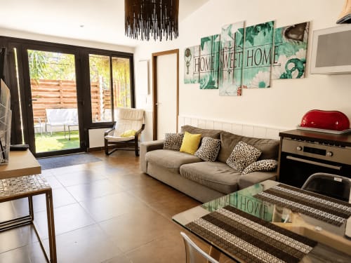 Licht woonkamer in Péret cottage met beige sofa, tuindeuren en moderne voorzieningen