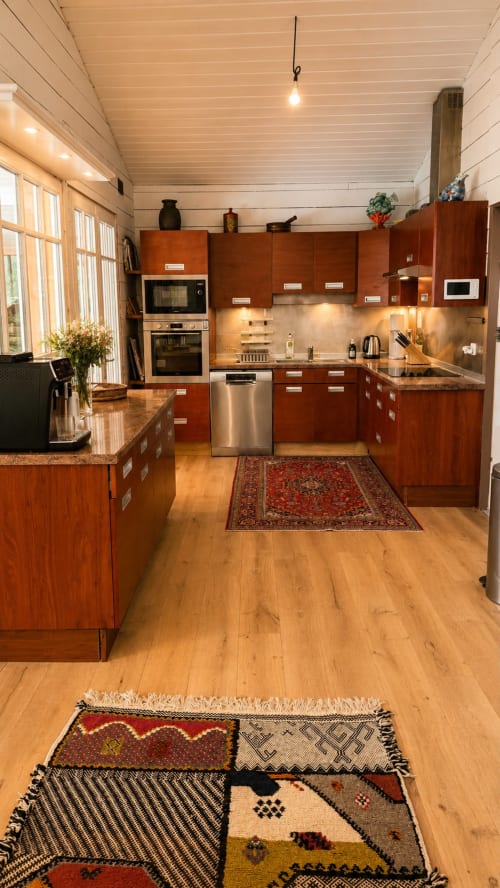 Cuisine moderne à la villa La Chunga : meubles en bois clair, appareils inox, plan de travail en granit, lumière naturelle