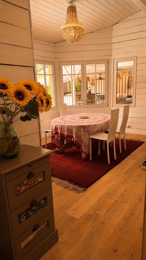 Élégante salle à manger de la Villa La Chunga avec table ronde, lustre à perles, tournesols et vue sur le jardin à Lège-Cap-Ferret