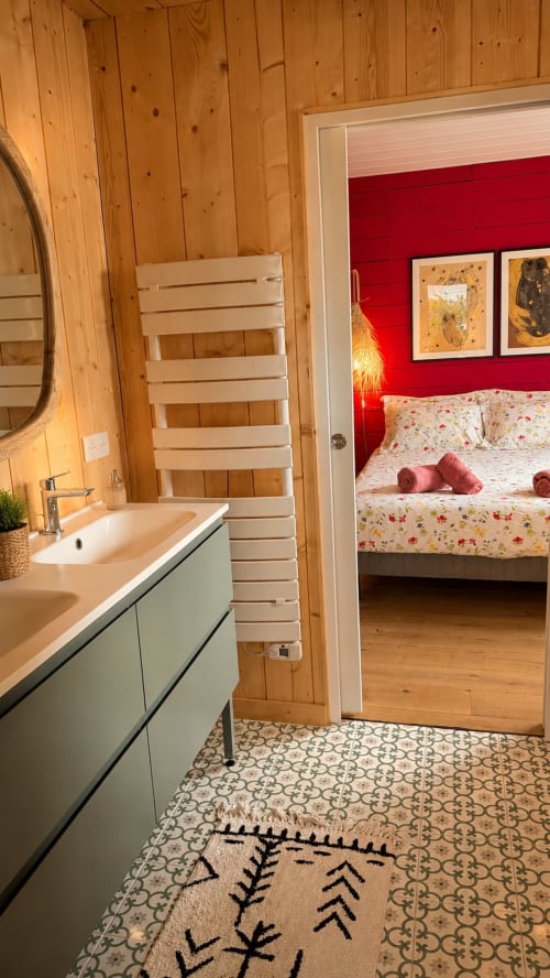 Vue de la salle de bain et chambre à la villa La Loge Du Bassin à Lège-Cap-Ferret avec murs en bois, lavabo moderne, mur d'accent rouge et