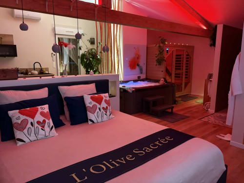 Suite de luxe L'Olive Sacrée à Cabannes avec éclairage rose, lit king-size, sauna et équipements spa