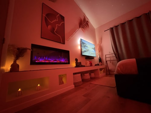 Suite moderne à l'hôtel Suite & Duplex en Provence avec éclairage ambiant rouge, cheminée, télévision et décoration contemporaine