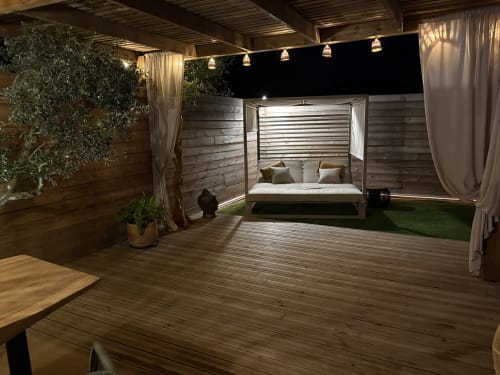 Suite chambre extérieure luxe à L'Olive Sacrée en Provence : lit à baldaquin, éclairage ambiant, terrasse bois et vue sur jardin