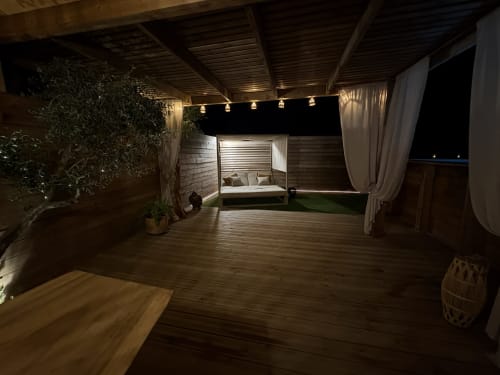Terrasse luxueuse illuminée de Suite l'Olive Sacrée en Provence avec lit à baldaquin, terrasse en bois et vue sur le jardin
