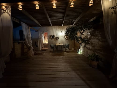 Élégante terrasse du soir à Suite l'Olive Sacrée en Provence, avec éclairage ambiant, zone de repas et verdure luxuriante